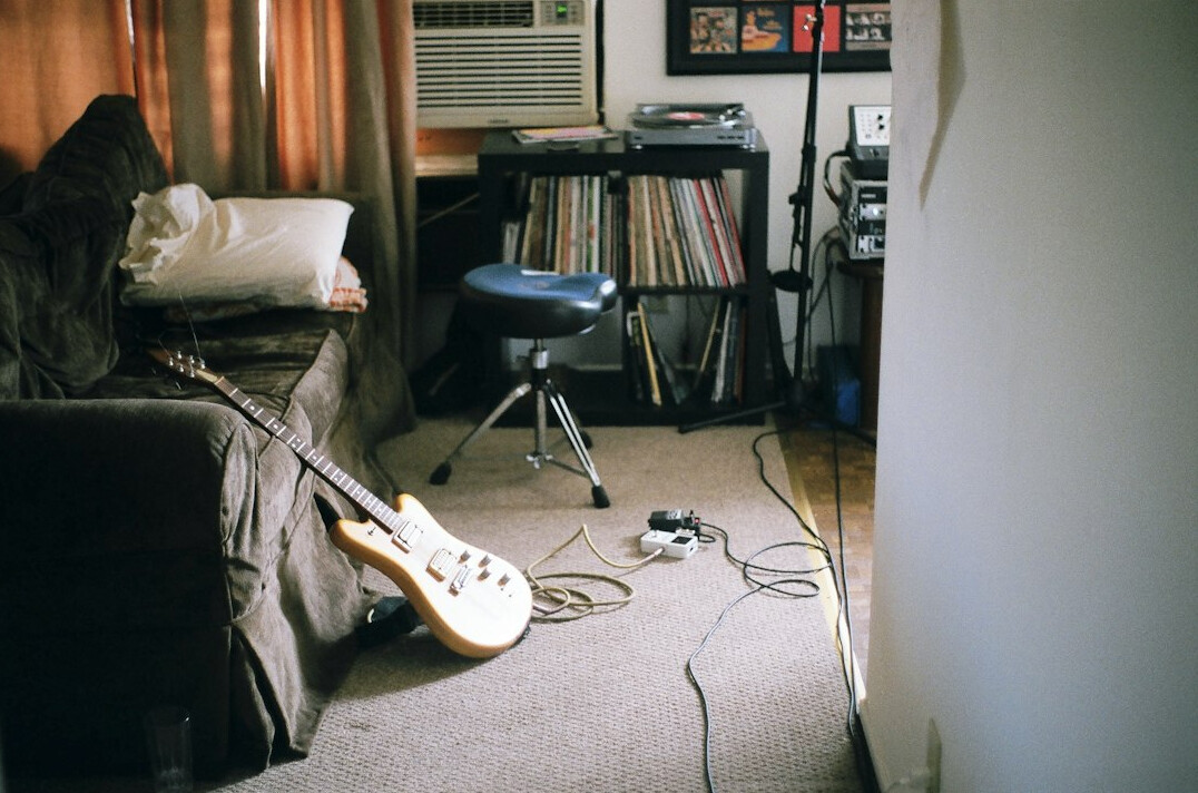 Vintage 1980s home recording studio with analog mixing console and guitars on the wall